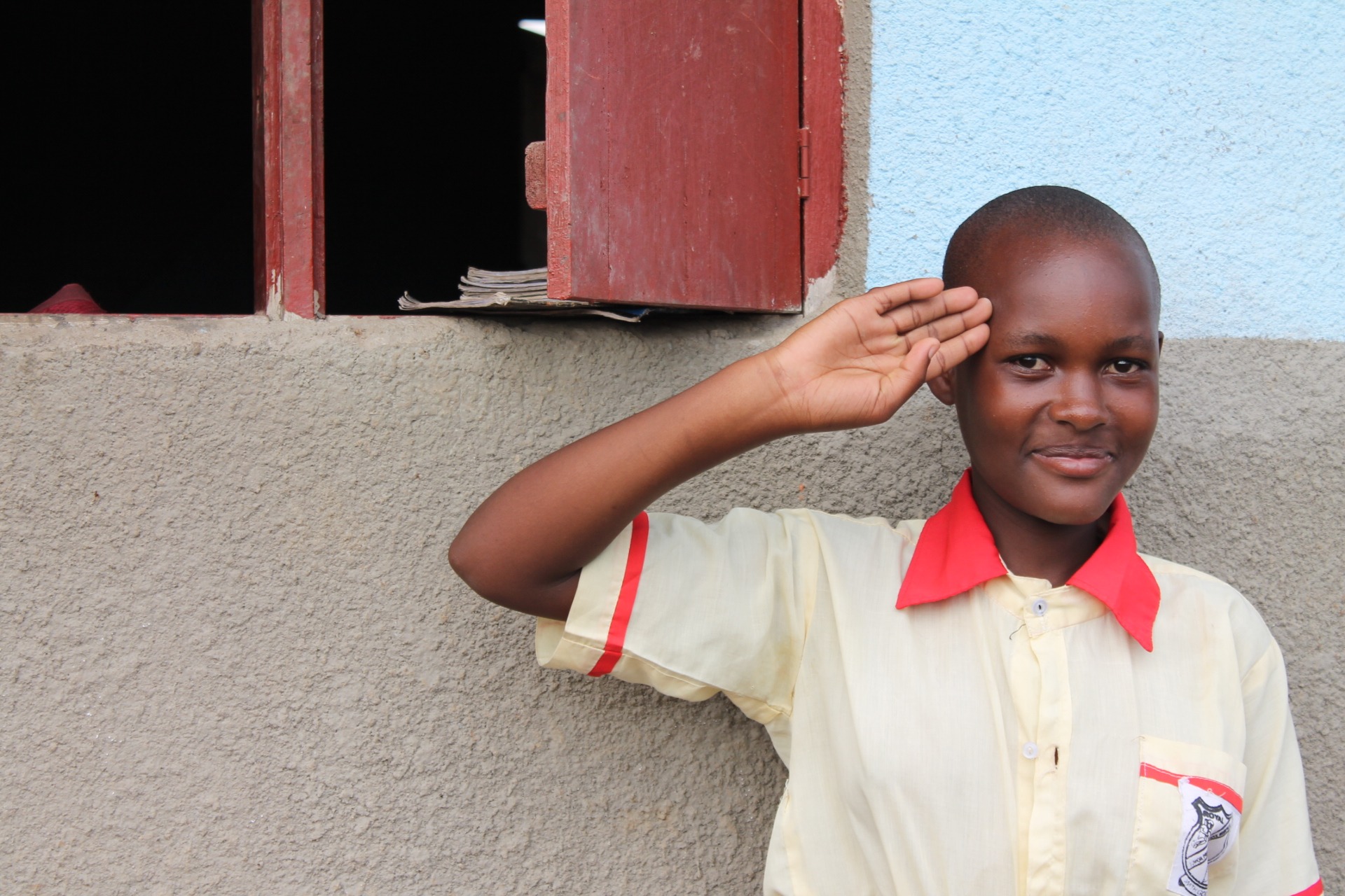 A Ugandan schoolgirl smiling and raising her hand