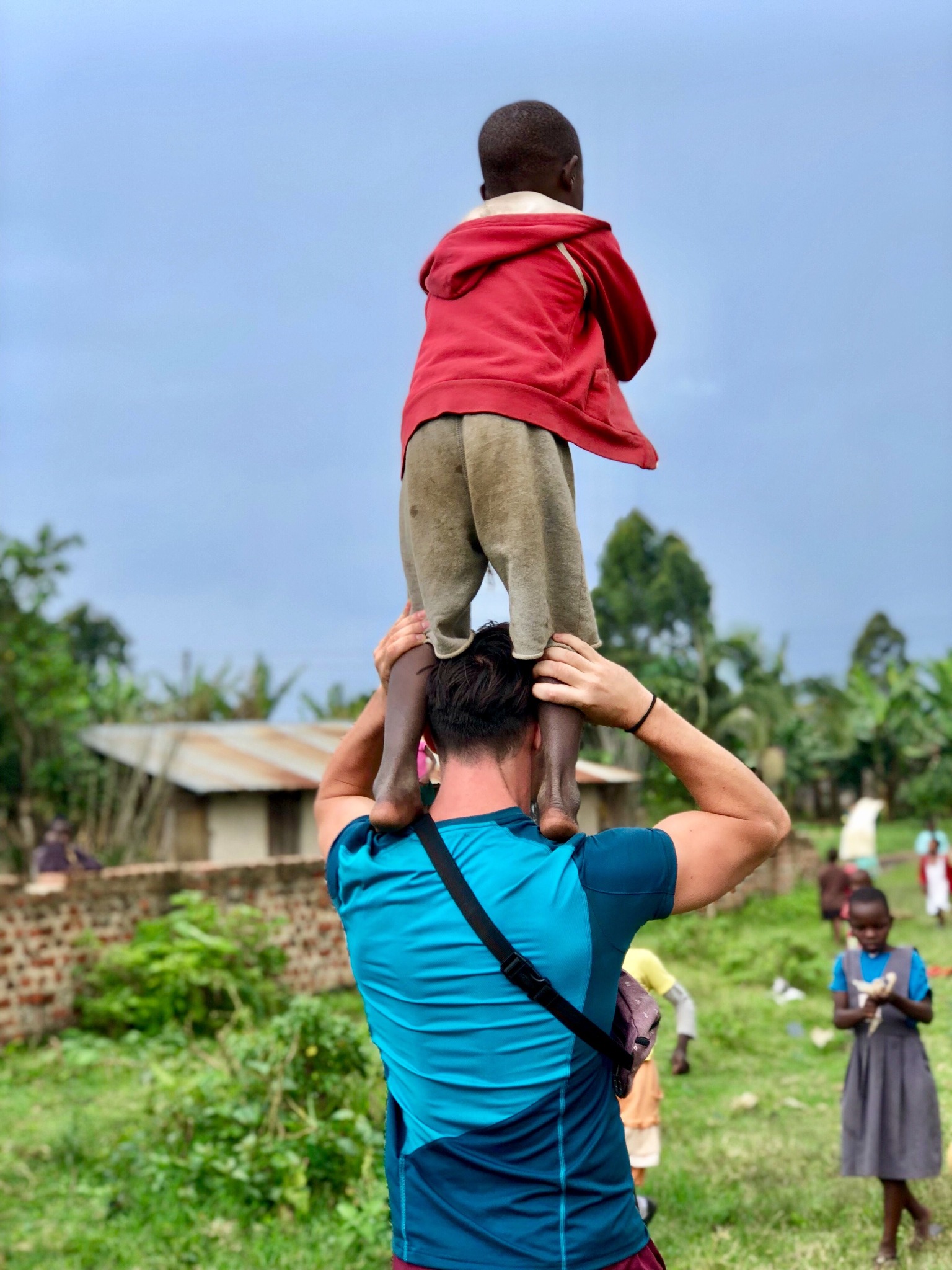A man carrying a child during a community visit